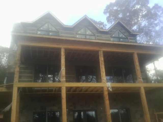 Dormers and porch framing on a large log home under construction — Roof Coating work by our crew in New Waverly