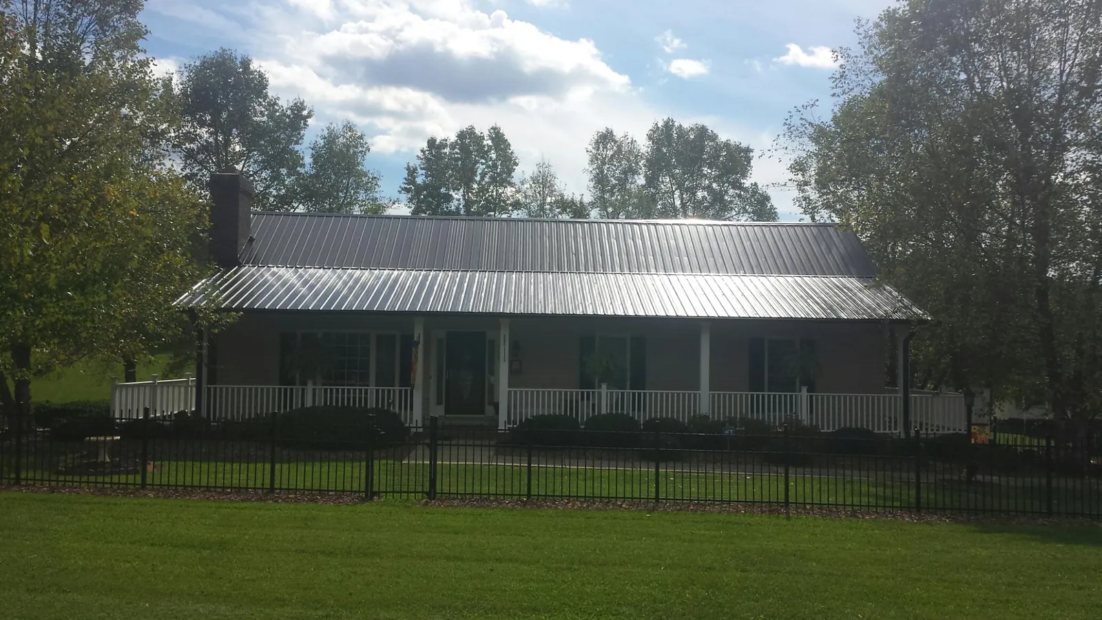 Gray metal roof on a brick ranch with a full width front porch — Gutter Guard Installation work by our crew in New Waverly