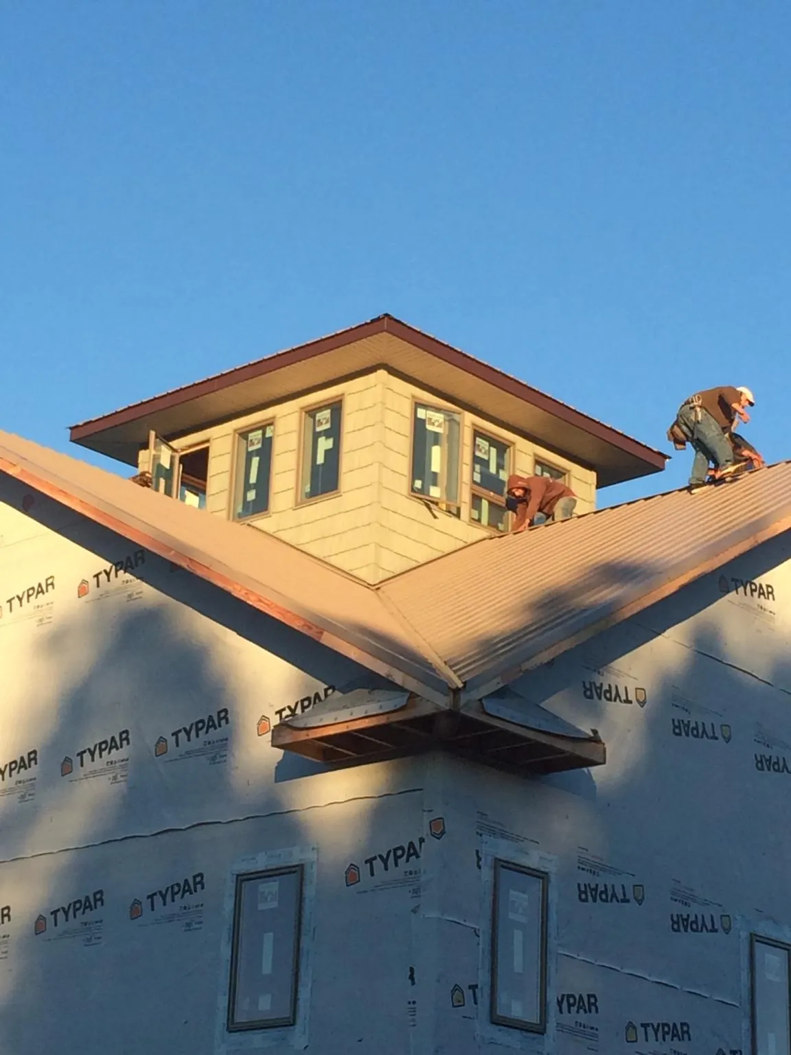 Roofers working around a rooftop cupola on a new metal roof at sunset — Roof Waterproofing in New Waverly by Roofing Brothers